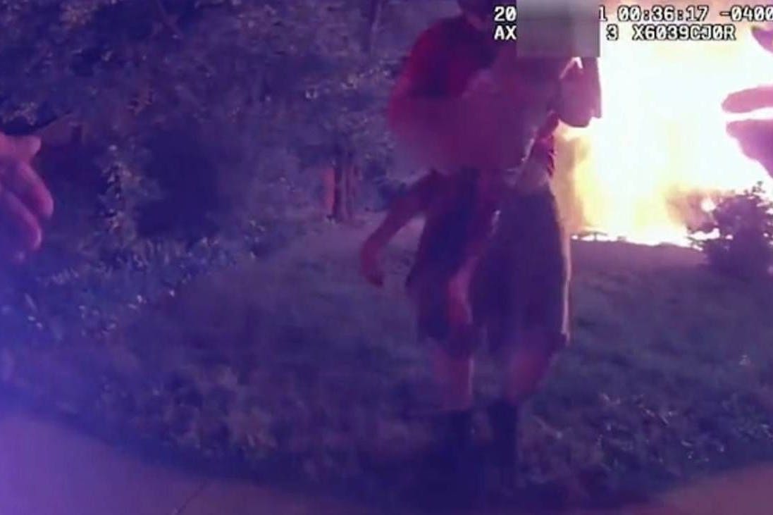 Polizeikameras filmen, wie Nicolas Bostic ein Mädchen aus dem brennenden Haus rettet.