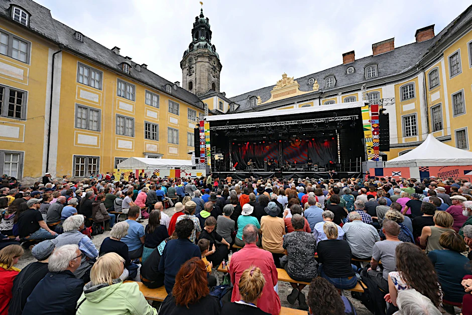 Besucher sitzen im Innenhof der Heidecksburg beim Konzert der Gruppe Light in Babylon aus Istanbul (Türkei) beim Rudolstadt Festival.  