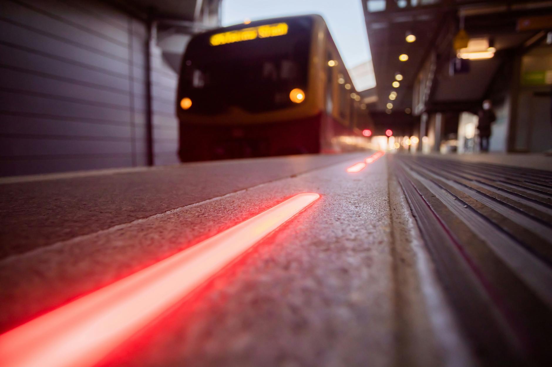 Die leuchtende Bahnsteigkante an Gleis 1 im Bahnhof Berlin Südkreuz in Aktion. Rotes Blinken zeigt: Eine S-Bahn fährt ein.
