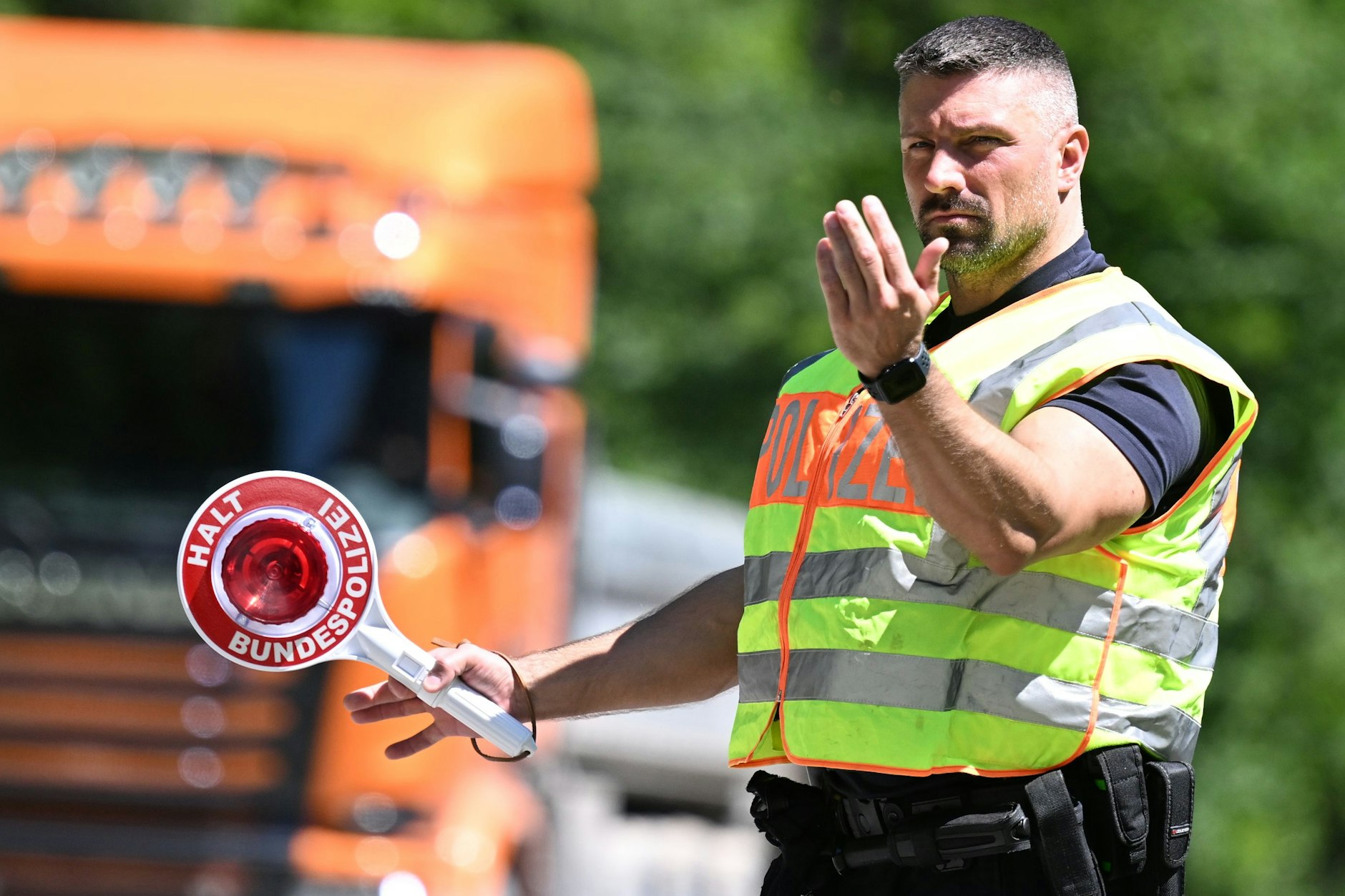 Ein Polizist stoppt auf einem Autobahnparkplatz ein Fahrzeug. (Symbolbild)
