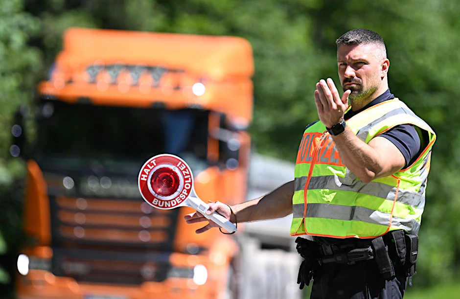 Ein Polizist stoppt auf einem Autobahnparkplatz ein Fahrzeug. (Symbolbild)