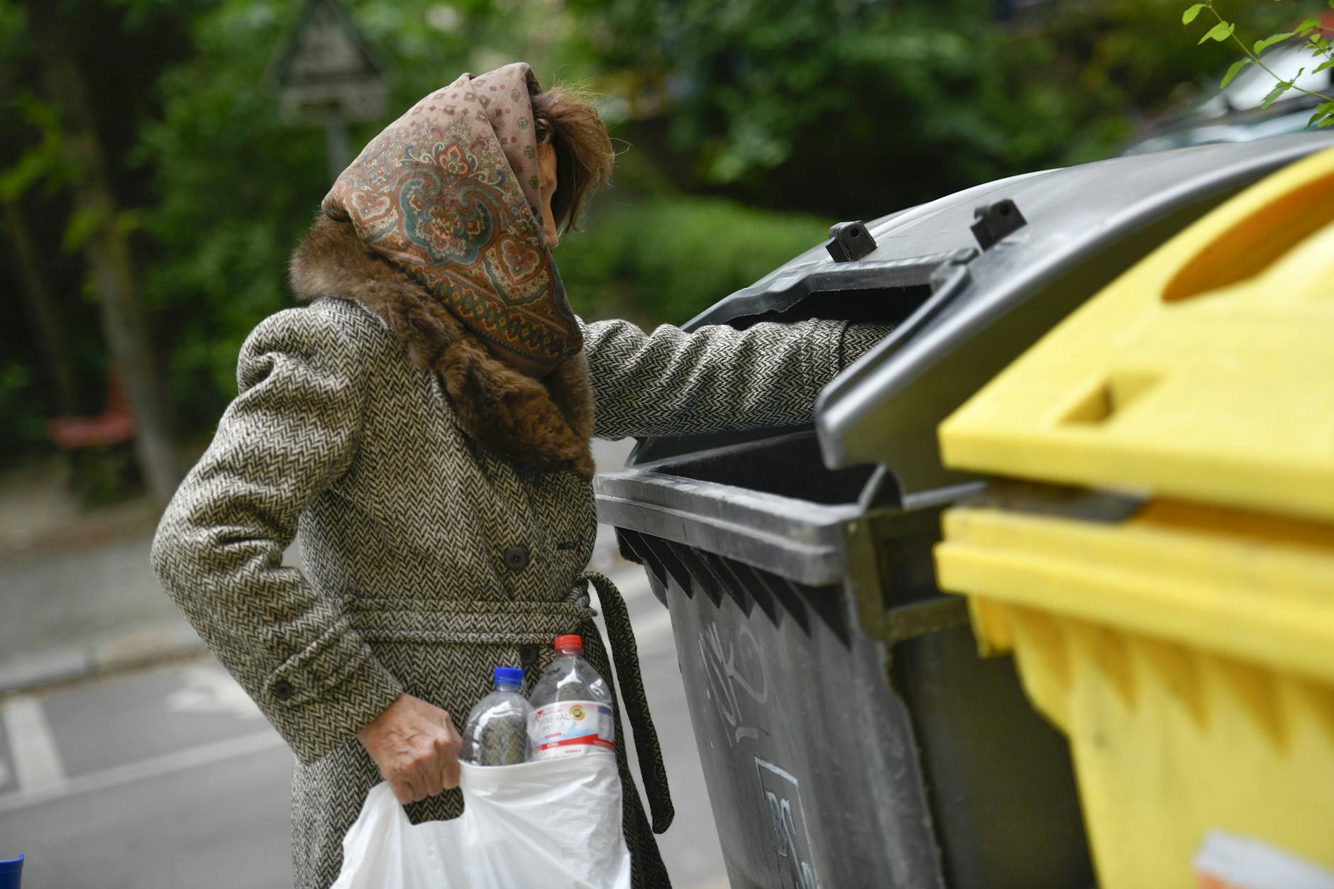 Eine Seniorin sammelt Flaschen.