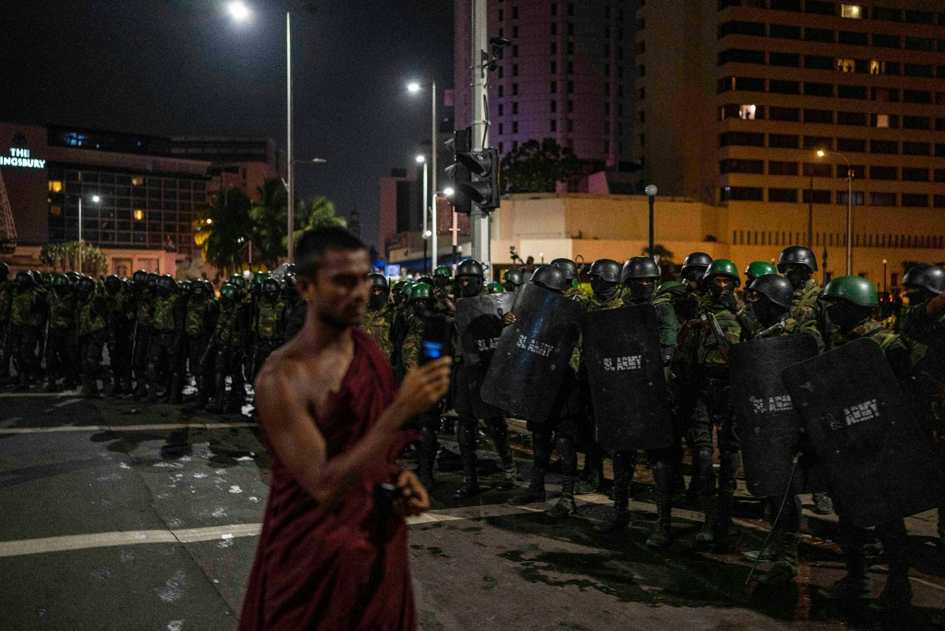 Ein buddhistischer Mönch filmt, wie Soldaten die Demonstranten vom Gelände eines Protestcamps in Colombo entfernen.  