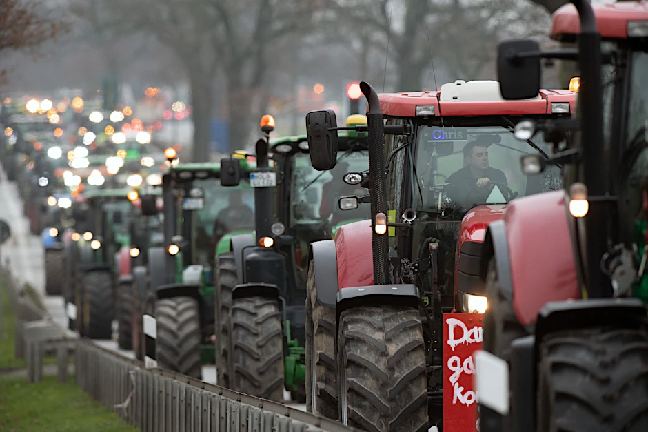 Landwirte fahren mit ihren Traktoren auf einer Straße zur Protestaktion.