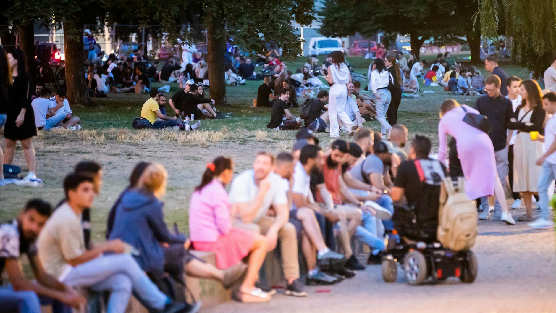 Besucher sitzen zusmmen auf einem Mäuerchen, kurz vor dem in Kraft treten des Alkoholverbots im James-Simon-Park im Berliner Bezirk Mitte.
