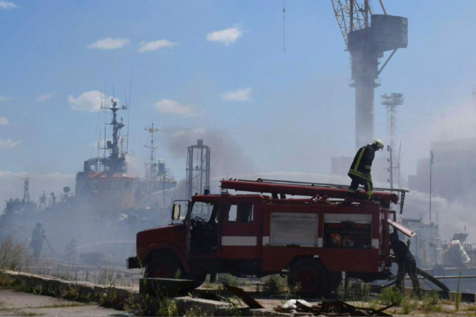 Ein Feuerwehrauto im Hafen von Odessa. Im Hintergrund verschießt ein Schlepper Löschwasser