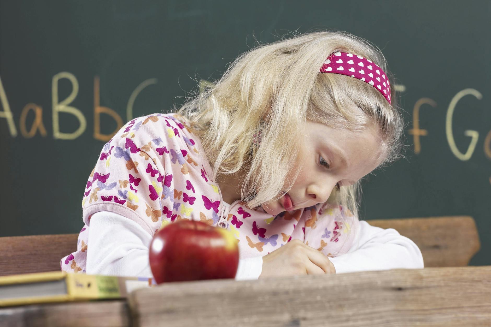 Ein Mädchen übt sehr konzentriert das Schreiben mit der Hand.