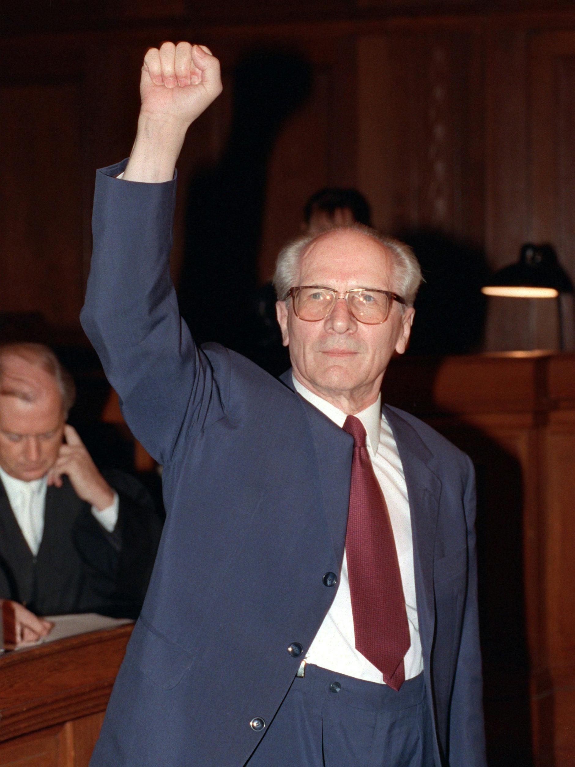 Mit hochgestreckter Faust: Im hellen Anzug, mit roter Krawatte erscheint Erich Honecker im Gerichtssaal.