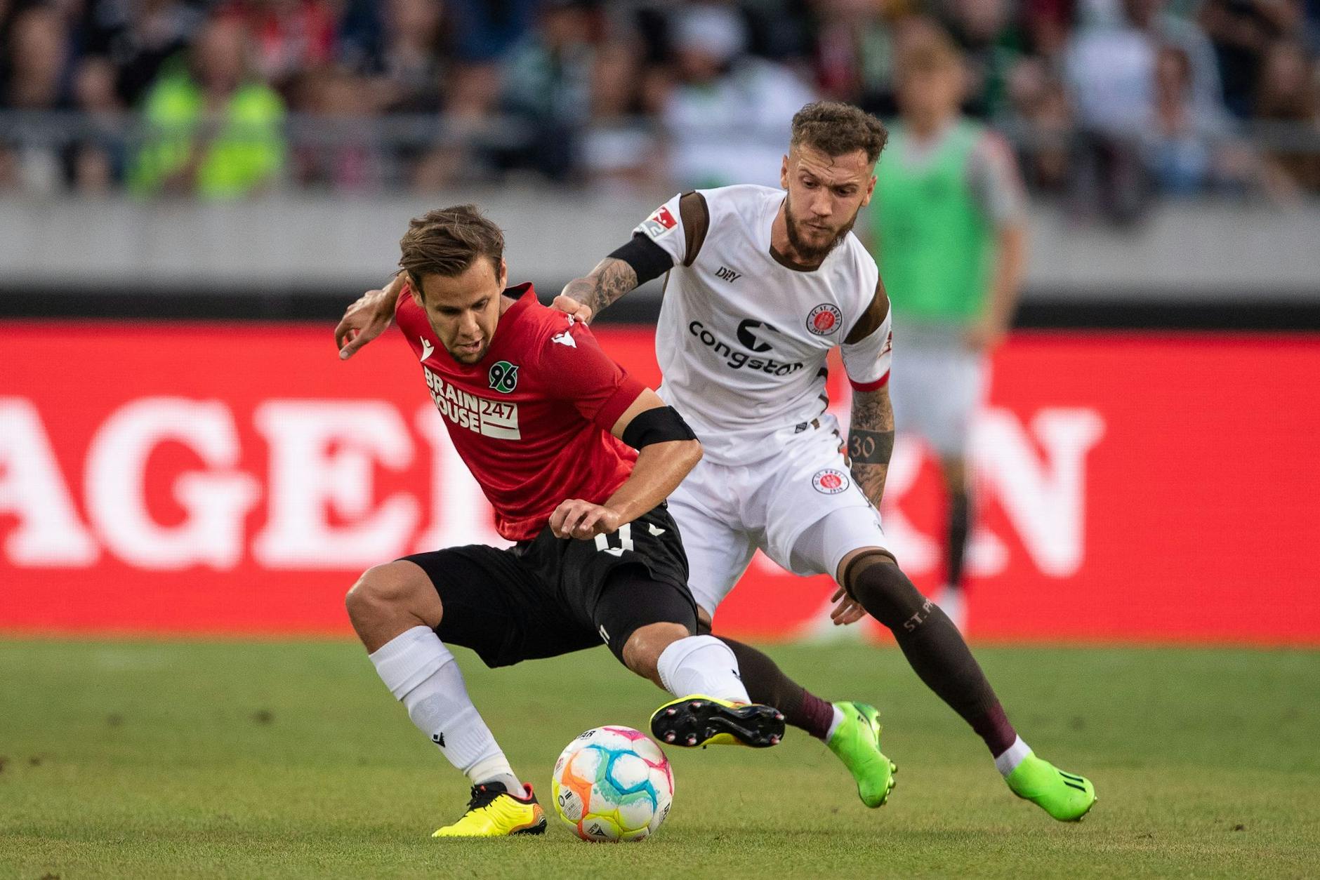 Louis Schaub (l) von Hannover 96 kämpft gegen St. Paulis Marcel Hartel um den Ballbesitz.