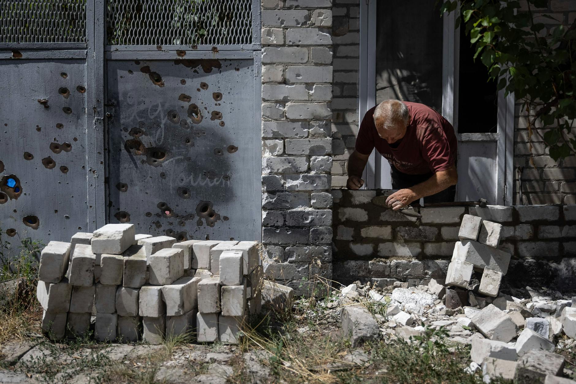 In der ukrainischen Stadt Rubischne flickt ein Mann eine Mauer notdürftig zusammen.
