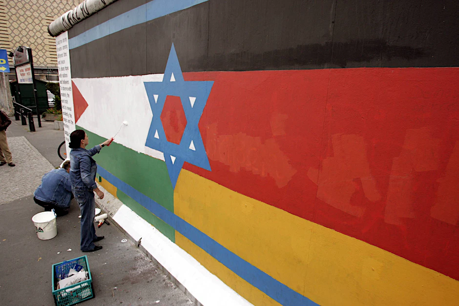 Maler und Fotograf Günther Schäfer und Malerin Varda Carmeli vereinigen unter dem Titel „Vaterland“ die Flaggen Israels, Palästinas und Deutschlands auf einem Mauerrest an der East Side Gallery in Berlin.