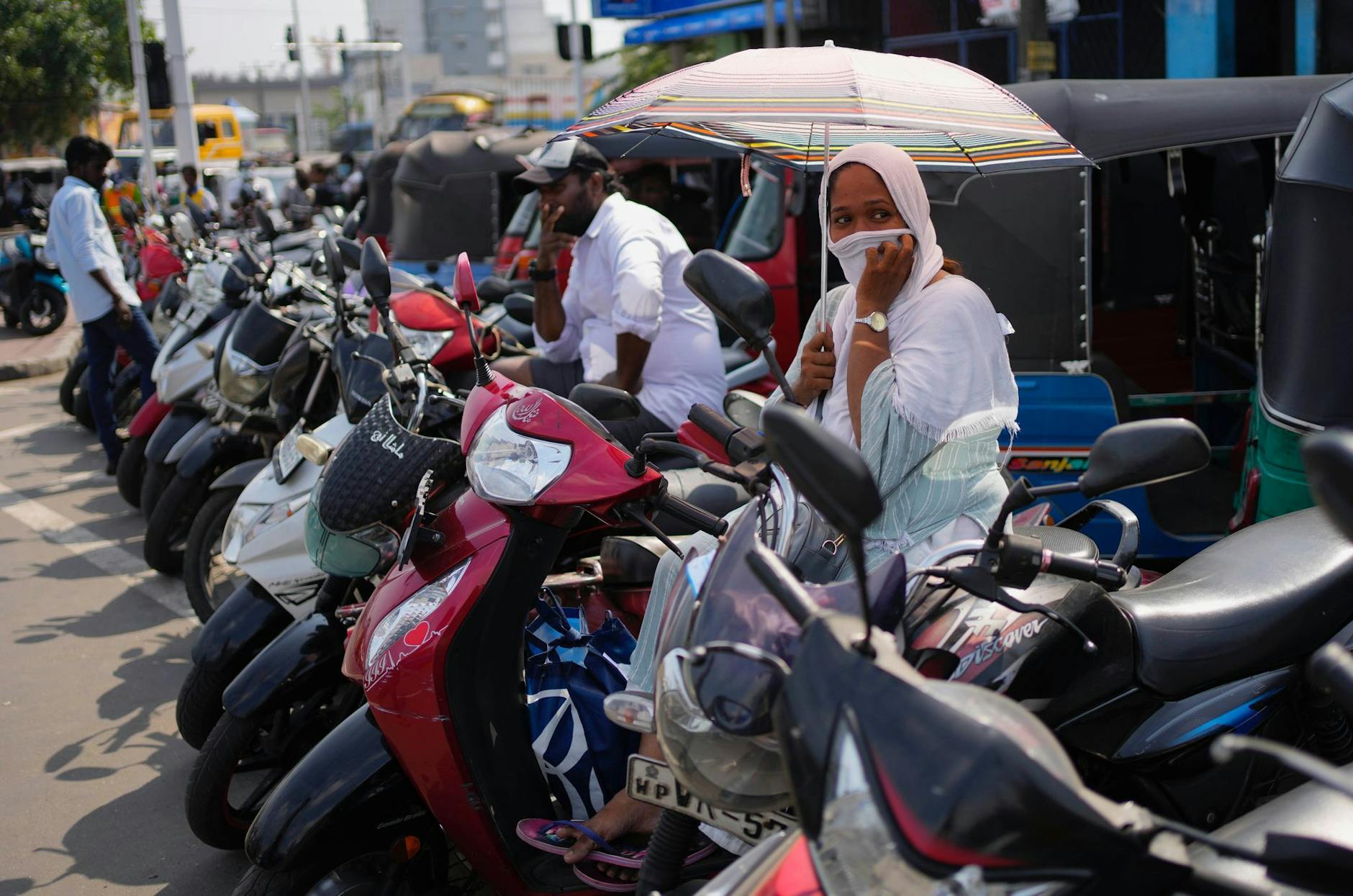 Menschen auf Motorrollern und Autorikschas warten an einer Tankstelle. Die Wirtschaftskrise in Sri Lanka hat dazu geführt, dass die 22 Millionen Einwohner des Landes mit einem Mangel an lebenswichtigen Gütern wie Medikamenten, Kraftstoff und Lebensmitteln zu kämpfen haben.