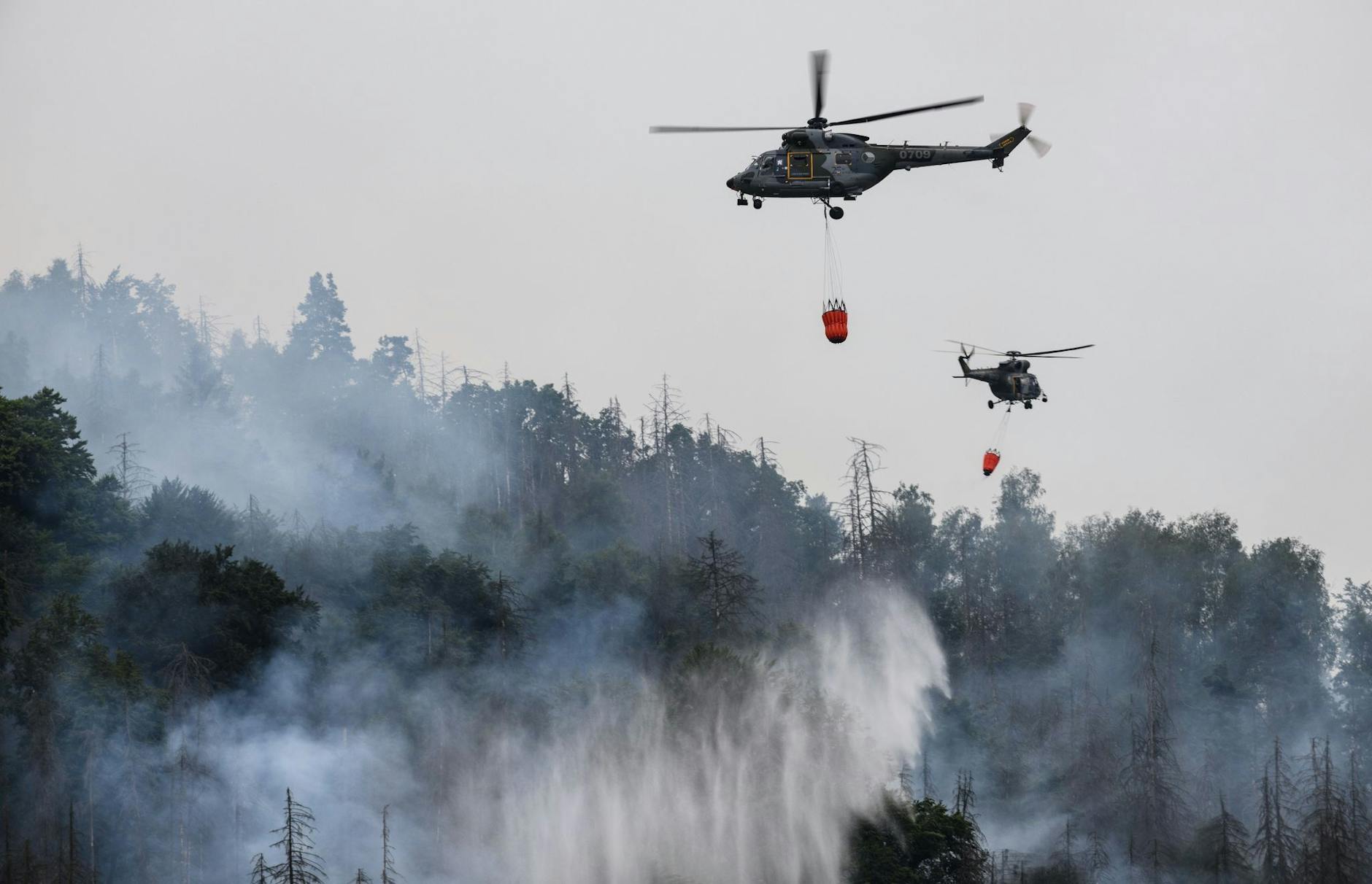 Mit Hubschraubern wird ein Waldbrand im tschechischen Nationalpark Böhmische Schweiz in Hrensko nahe der Grenze zu Sachsen gelöscht.