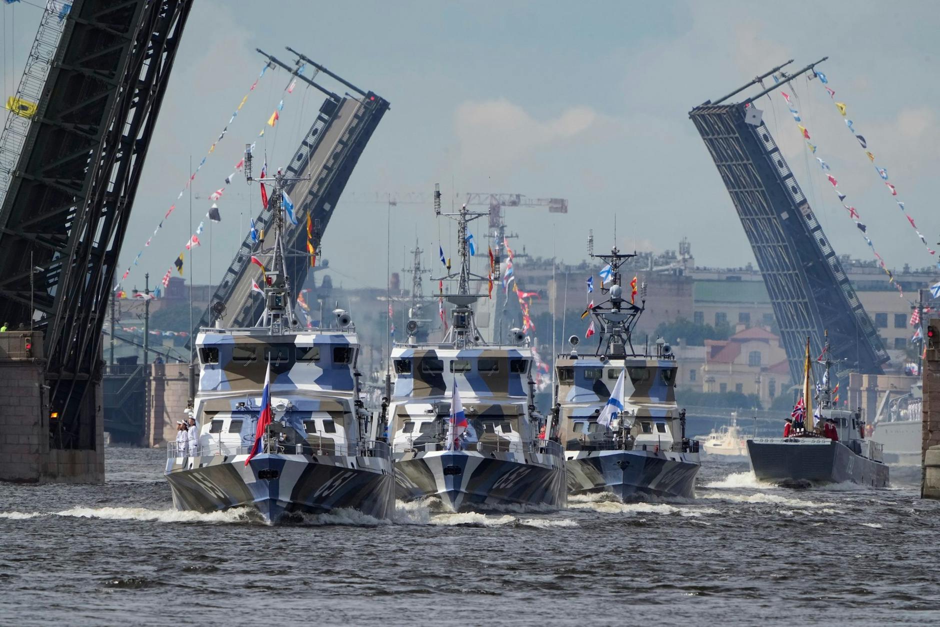 Kriegsschiffe fahren auf der Newa an hochgezogenen Zugbrücken in St. Petersburg vorbei.