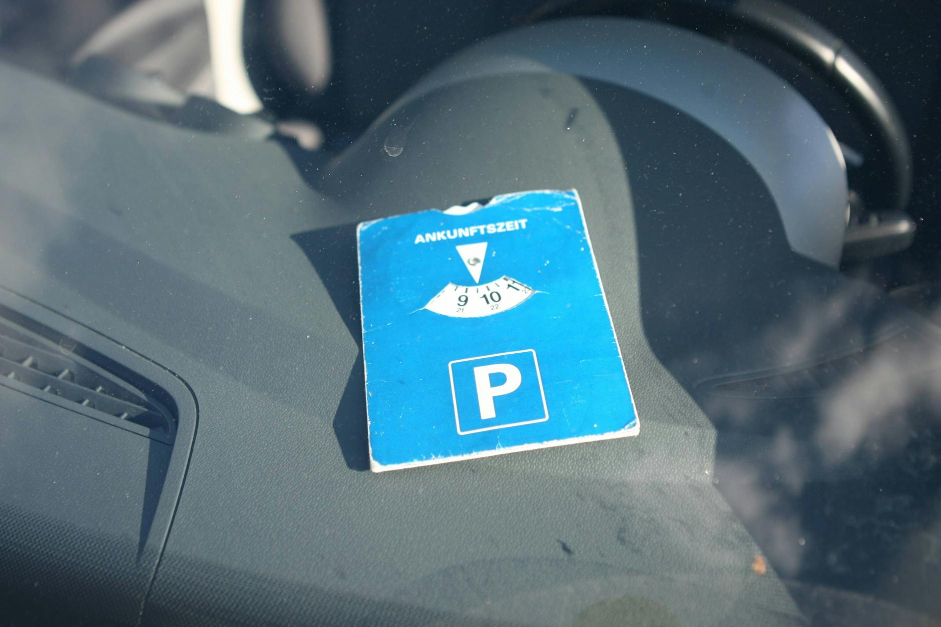 Eine Parkscheibe liegt in einem Auto. Und Achtung: Sie muss blau sein. Wenn sie pink ist, muss der Parkplatzbetreiber sie nicht berücksichtigen.
