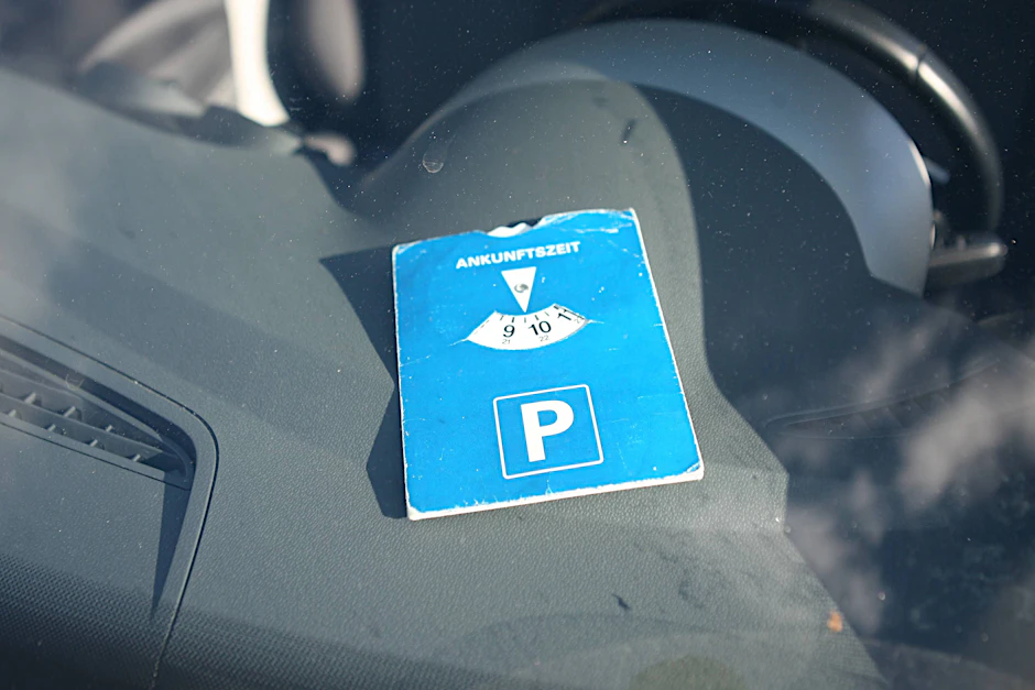 Eine Parkscheibe liegt in einem Auto. Und Achtung: Sie muss blau sein. Wenn sie pink ist, muss der Parkplatzbetreiber sie nicht berücksichtigen.