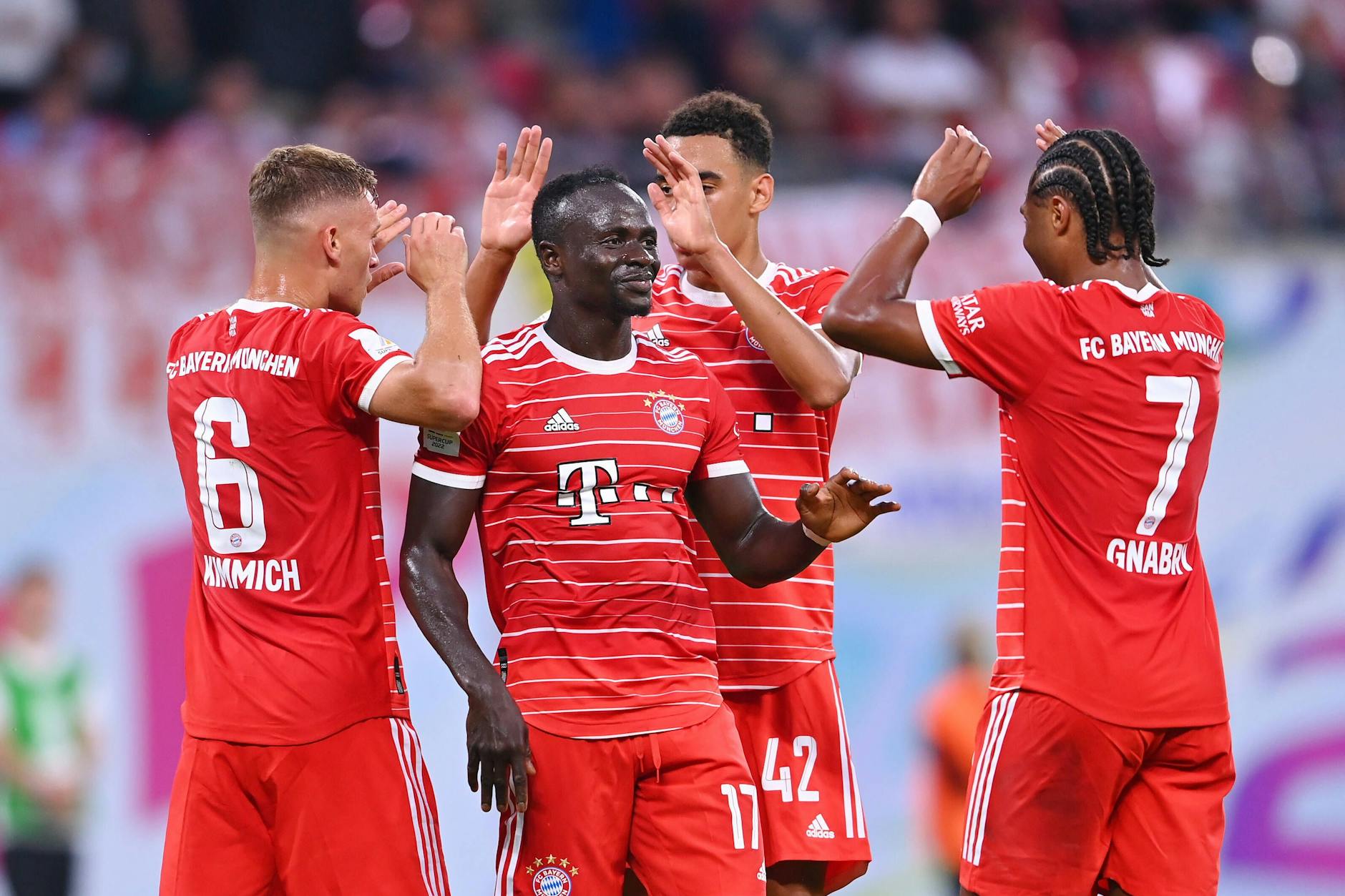 Joshua Kimmich, Serge Gnabry und Jamal Musiala gratulieren Sadio Mane zu seinem ersten Pflichtspieltor für den FC Bayern München.