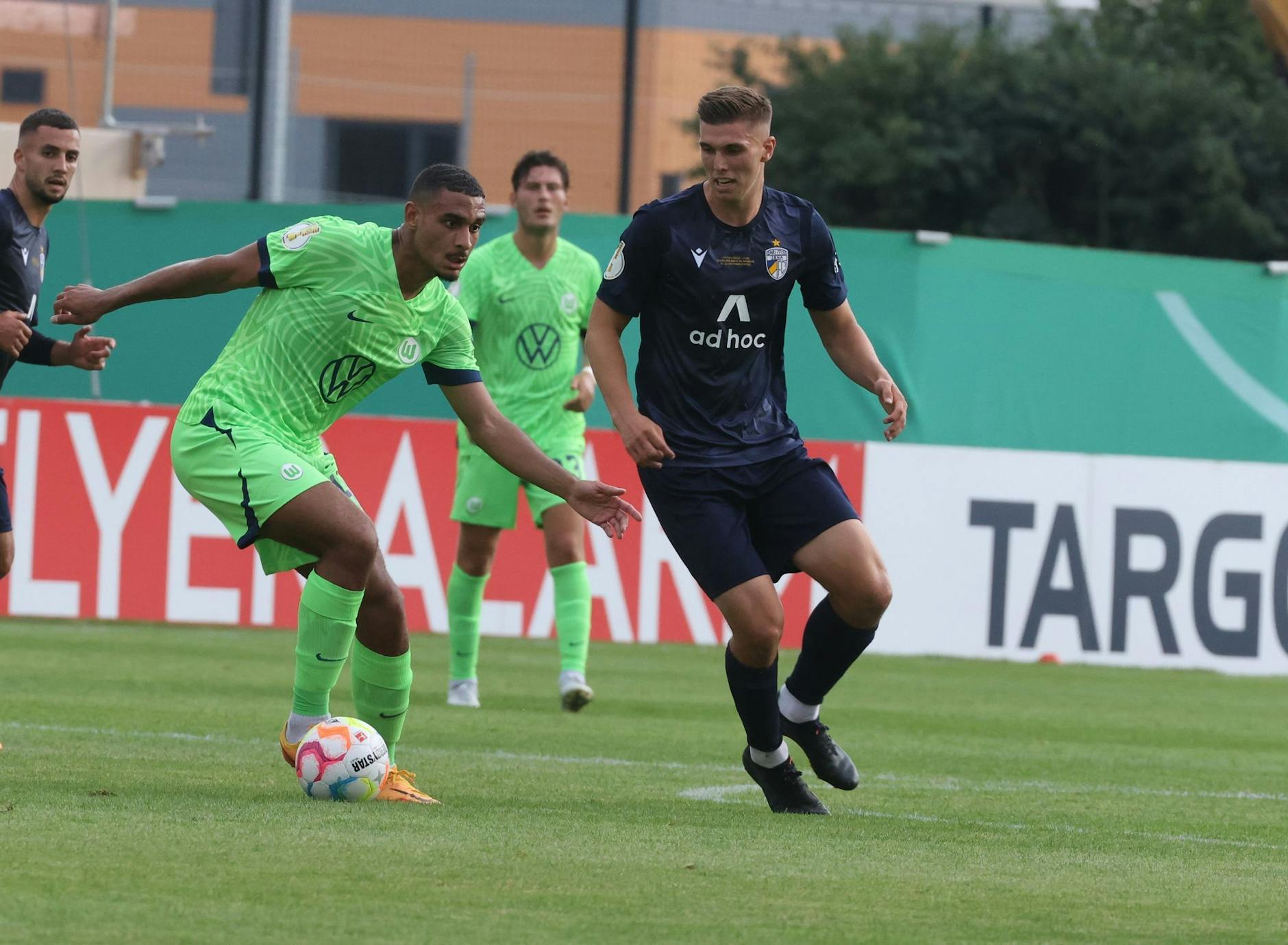 Wolfsburgs Maxence Lacroix (l) führt den Ball gegen Jenas Jan Dahlke eng am Fuß.