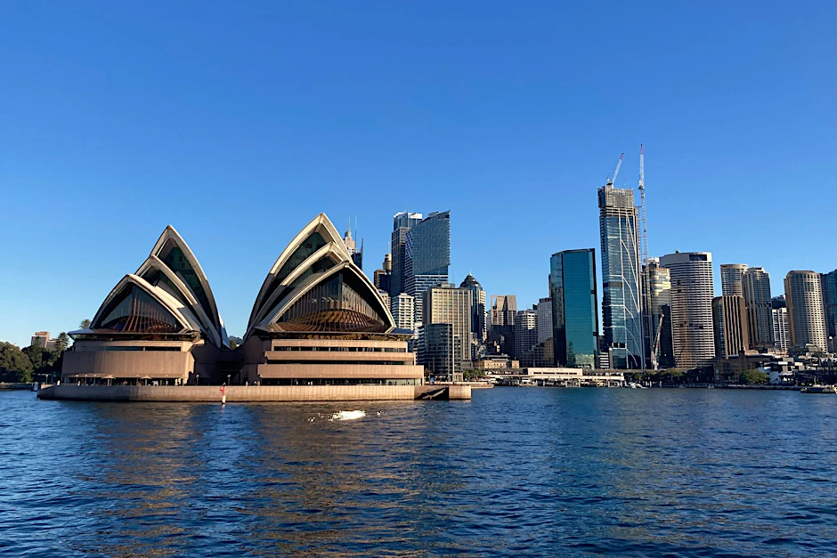 Das berühmte Sydney Opera House mit seinem segelförmigen Dach vor der Skyline der Stadt.  