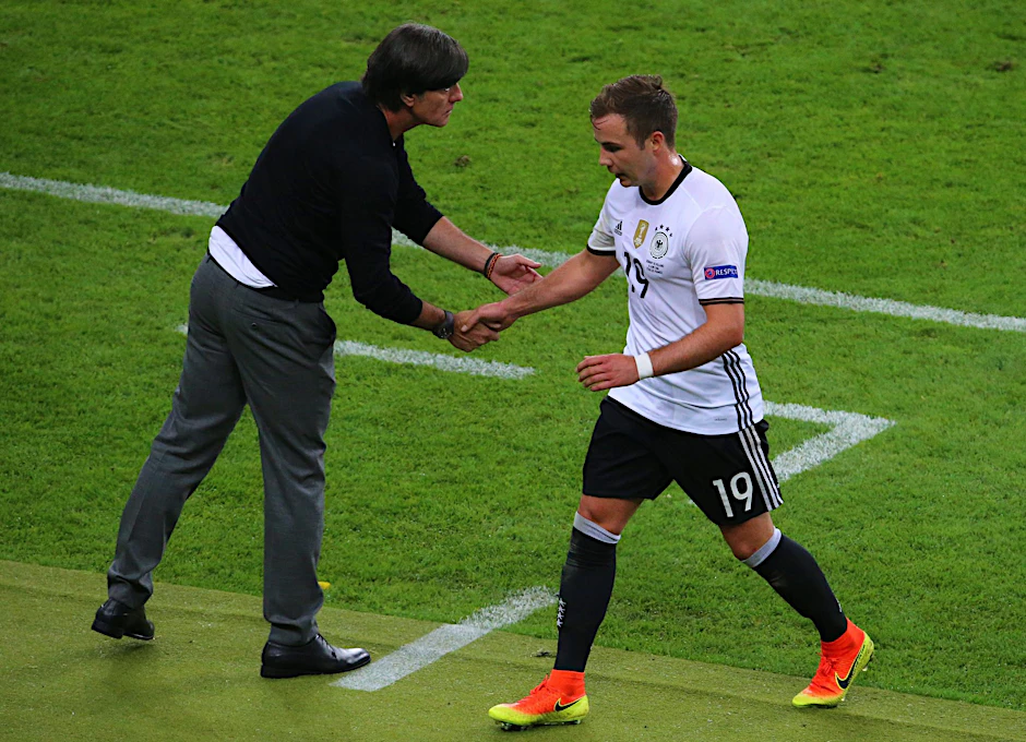 ARCHIV - Bei der EM 2016 gibt der damalige Bundestrainer Joachim Löw (l) Mario Götze bei dessen Auswechslung die Hand.  