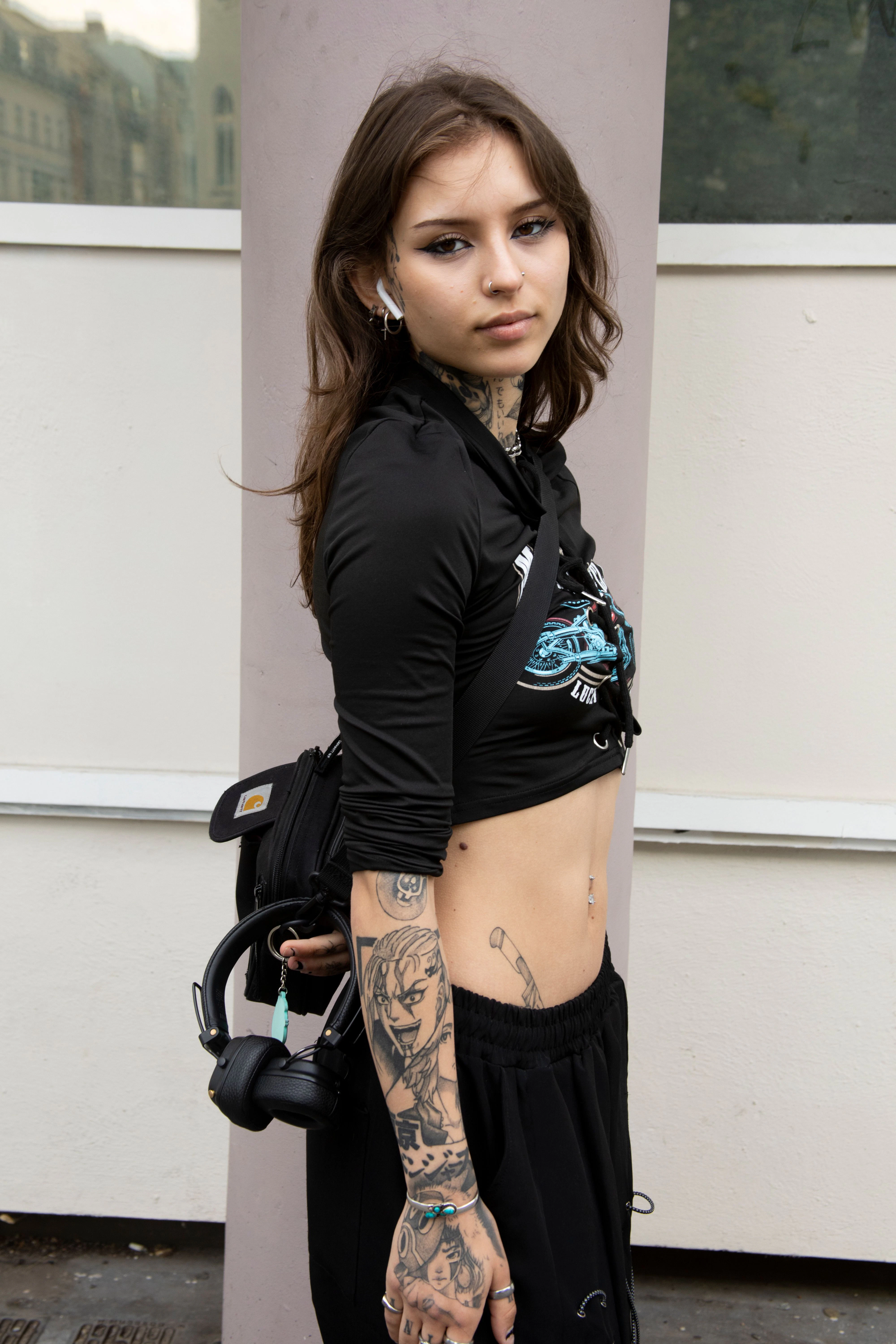 Das Crop Top hat Nora bei Shein gekauft, die Hose bei Cape Clique und die Schuhe sind Fake-Pradas aus der Türkei – erzählt sie lachend. Außerdem trägt sie eine Crossbody Bag von Carhartt und ganz viel Schmuck.