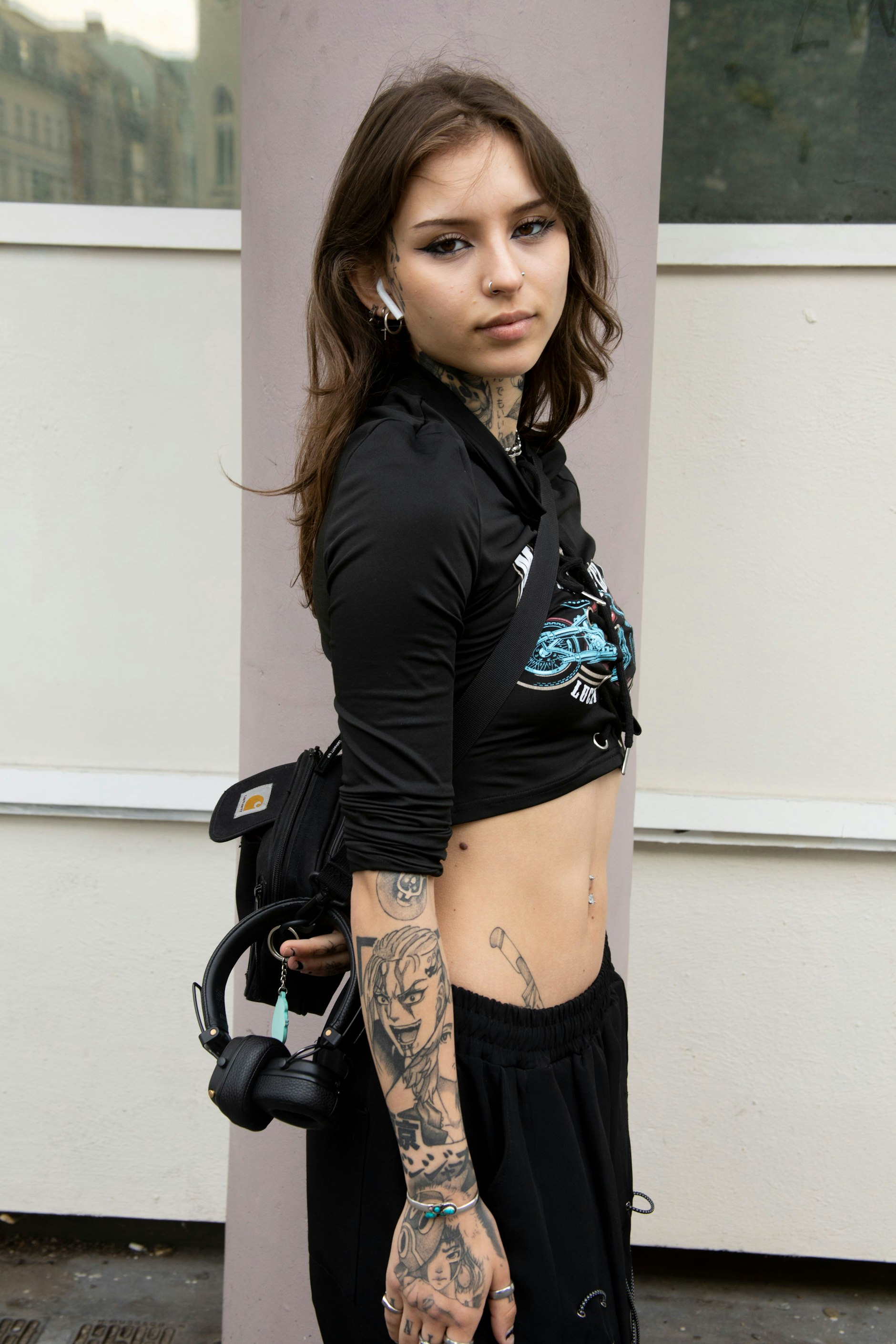 Das Crop Top hat Nora bei Shein gekauft, die Hose bei Cape Clique und die Schuhe sind Fake-Pradas aus der Türkei – erzählt sie lachend. Außerdem trägt sie eine Crossbody Bag von Carhartt und ganz viel Schmuck.