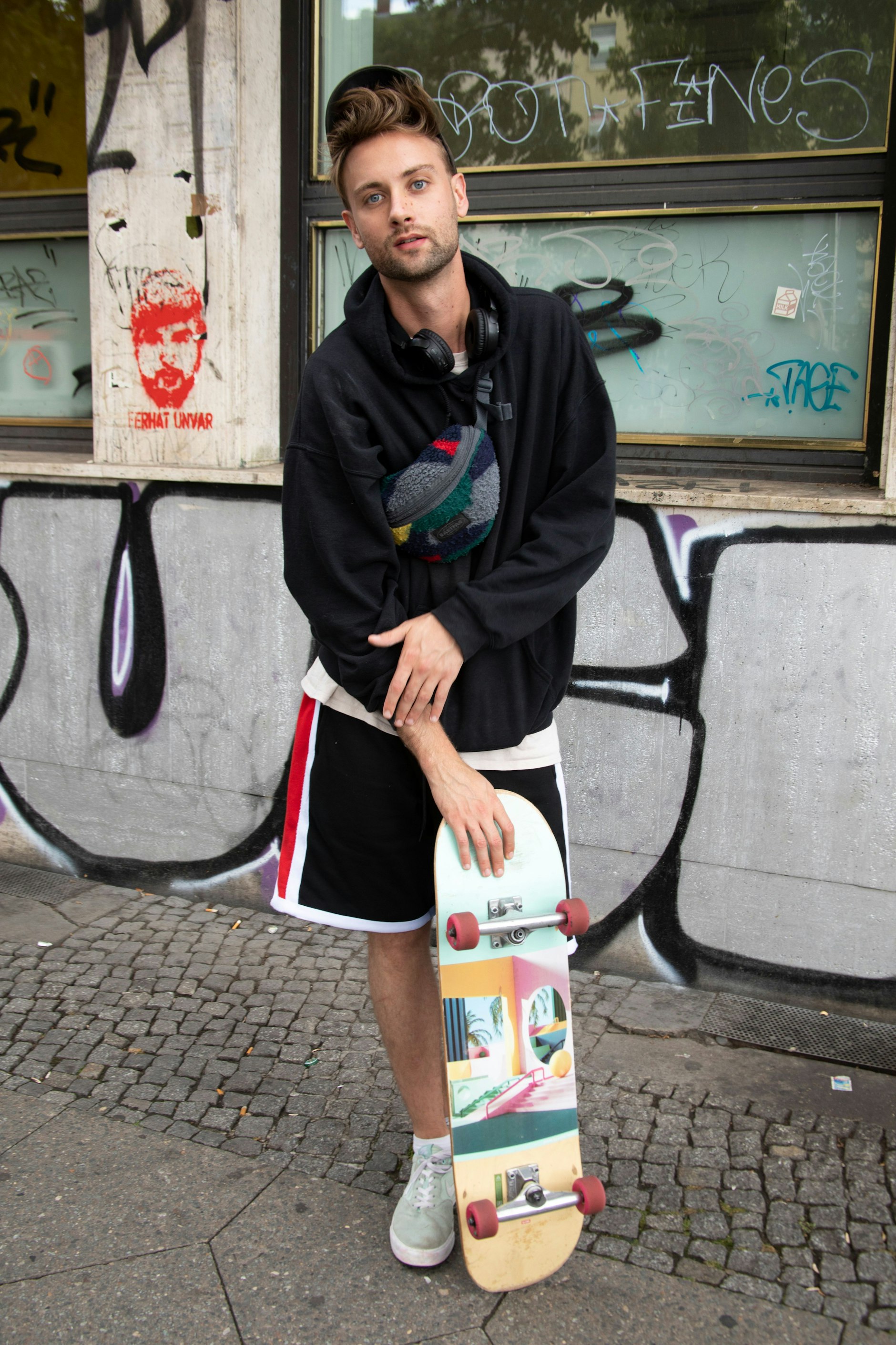 Fabi rollt gerade mit seinem Skateboard von der Arbeit nach Hause in den Wedding. Er arbeitet als Video-Producer und skatet gerne von A nach B. Sein „30-Euro-Outfit“, wie er es scherzhaft nennt, besteht aus T-Shirt, Hoody und Shorts. Die Labels sind in diesem Fall unwichtig. Nur beim Cap erkennen wir die Berliner Marke Vertere ...