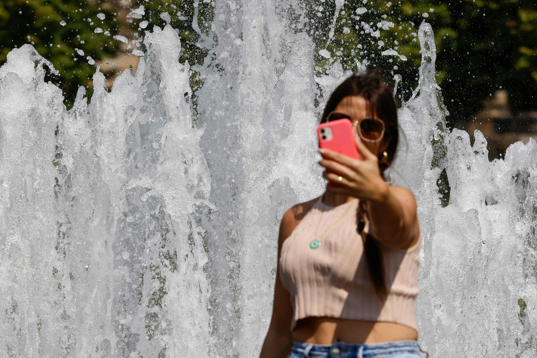 Alltägliches Straßenbild in Berlin: Eine Frau nimmt ein Selfie vor einem öffentlichen Brunnen auf.