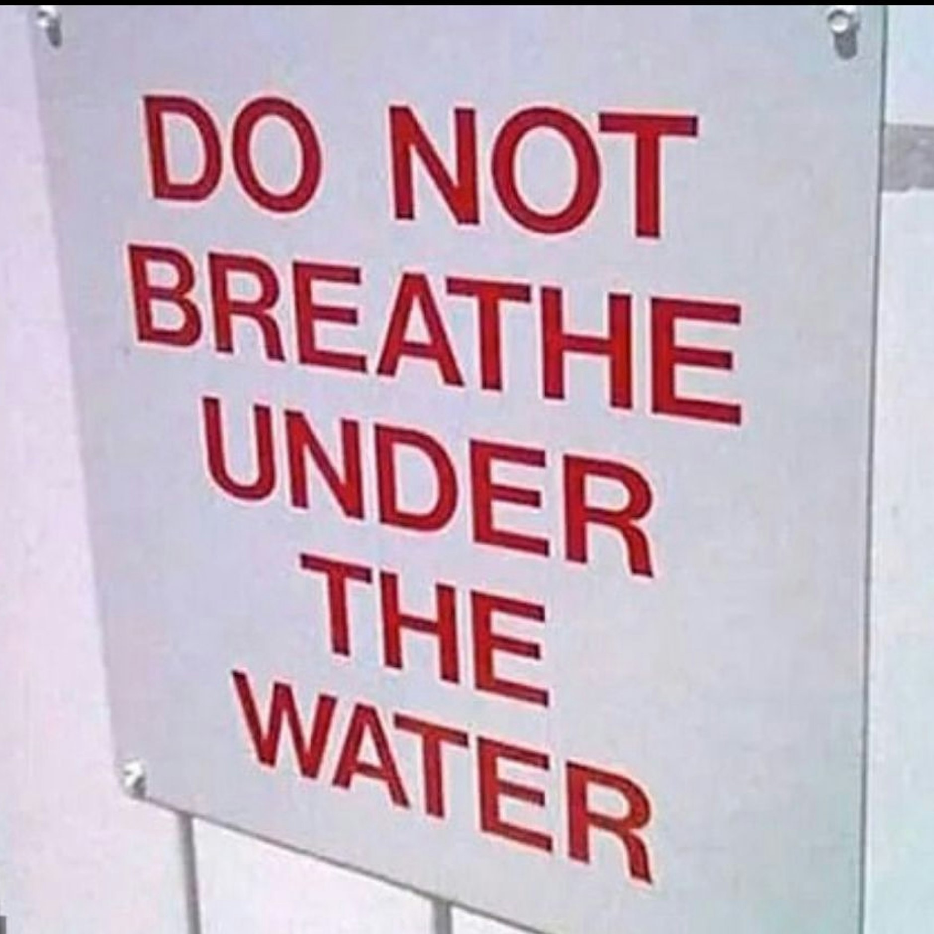 Schild mit der Aufschrift „Nicht unter Wasser atmen!“ vor dem Eingang zum Becken