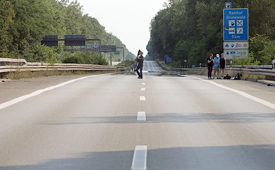 Ein Mann von einem Kamerateam geht, Höhe Abfahrt Hüttenweg, über die leere Autobahn A115.  