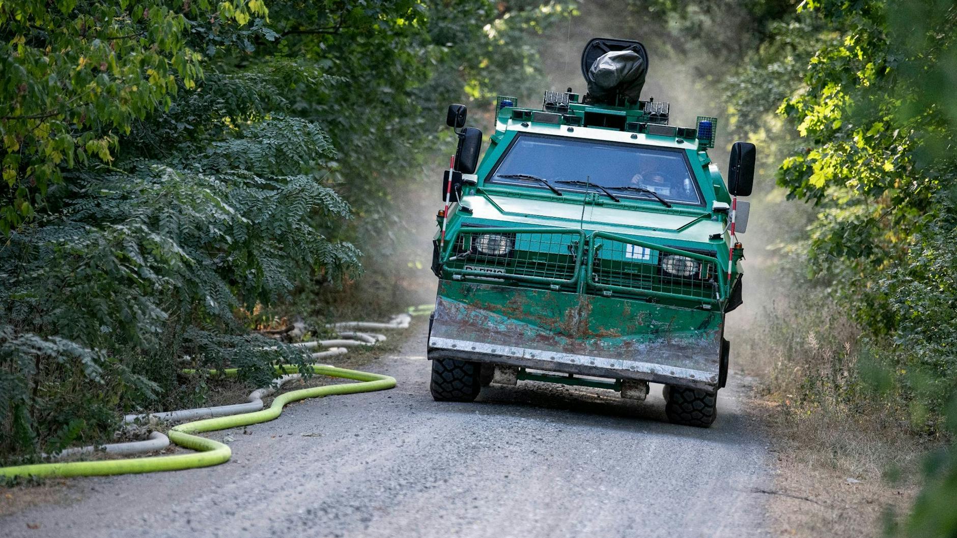 Ein Räumfahrzeug der Berliner Polizei fährt in der Nähe der Brandstelle am Sprengplatz im Grunewald einen Weg entlang.