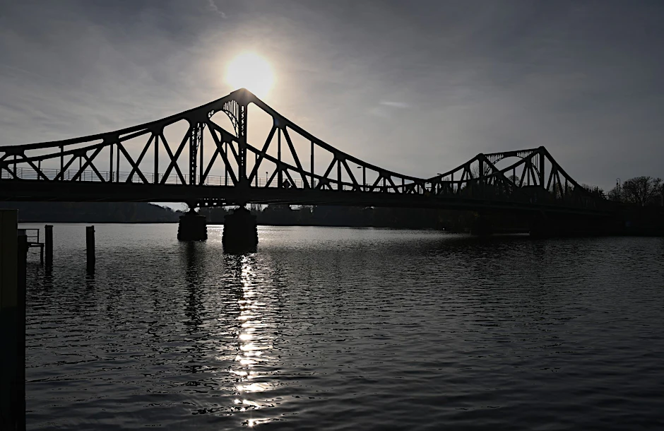 ARCHIV - Die Sonne geht vor der Veranstaltung zum Gedenken an die Wiedereröffnung der Glienicker Brücke unter.  d/Archivbild