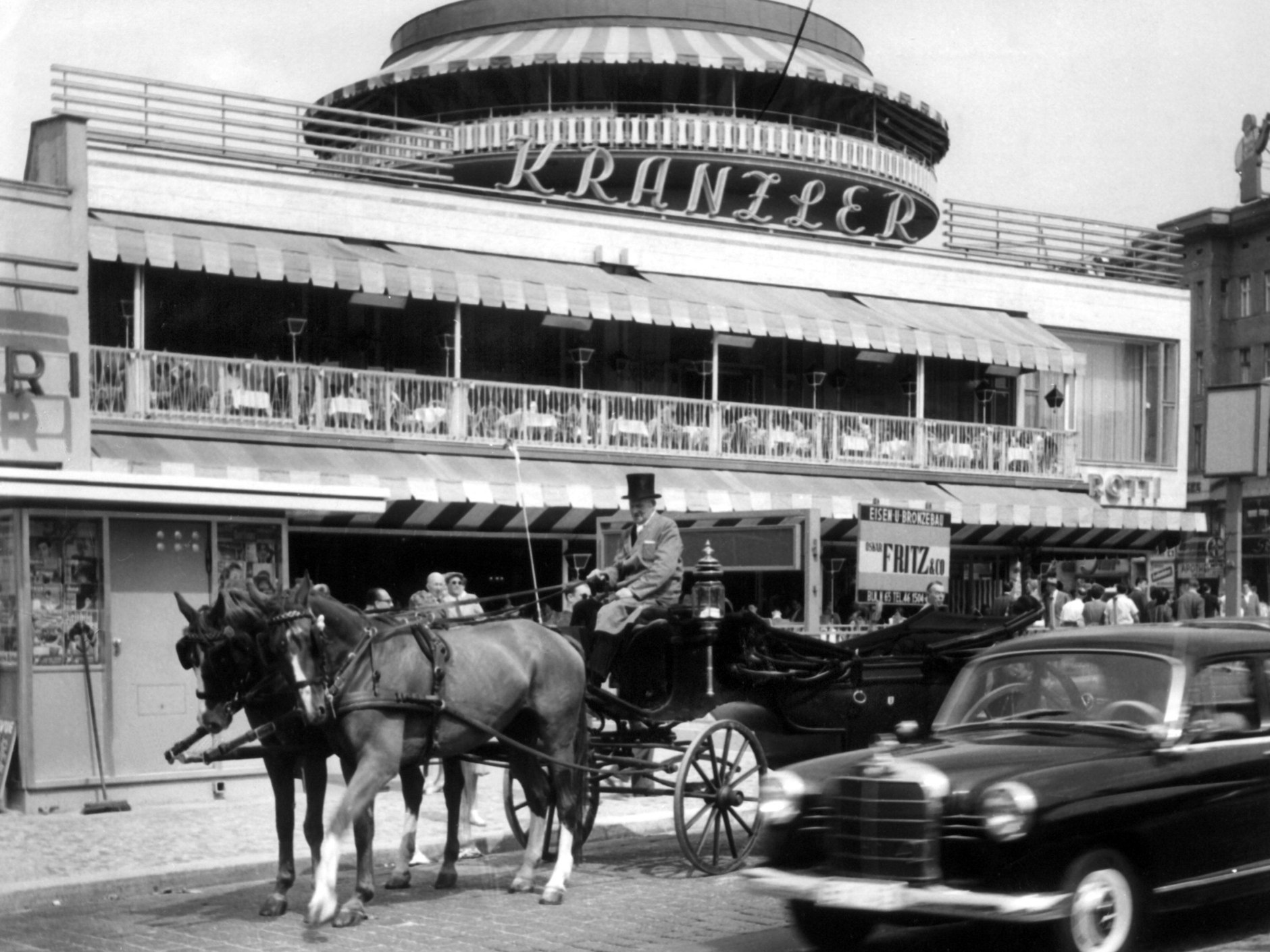 Eine Pferdekutsche und eine Mercedes-Limousine auf dem Kurfürstendamm in Berlin vor dem berühmten Café Kranzler (Foto von 1960).
