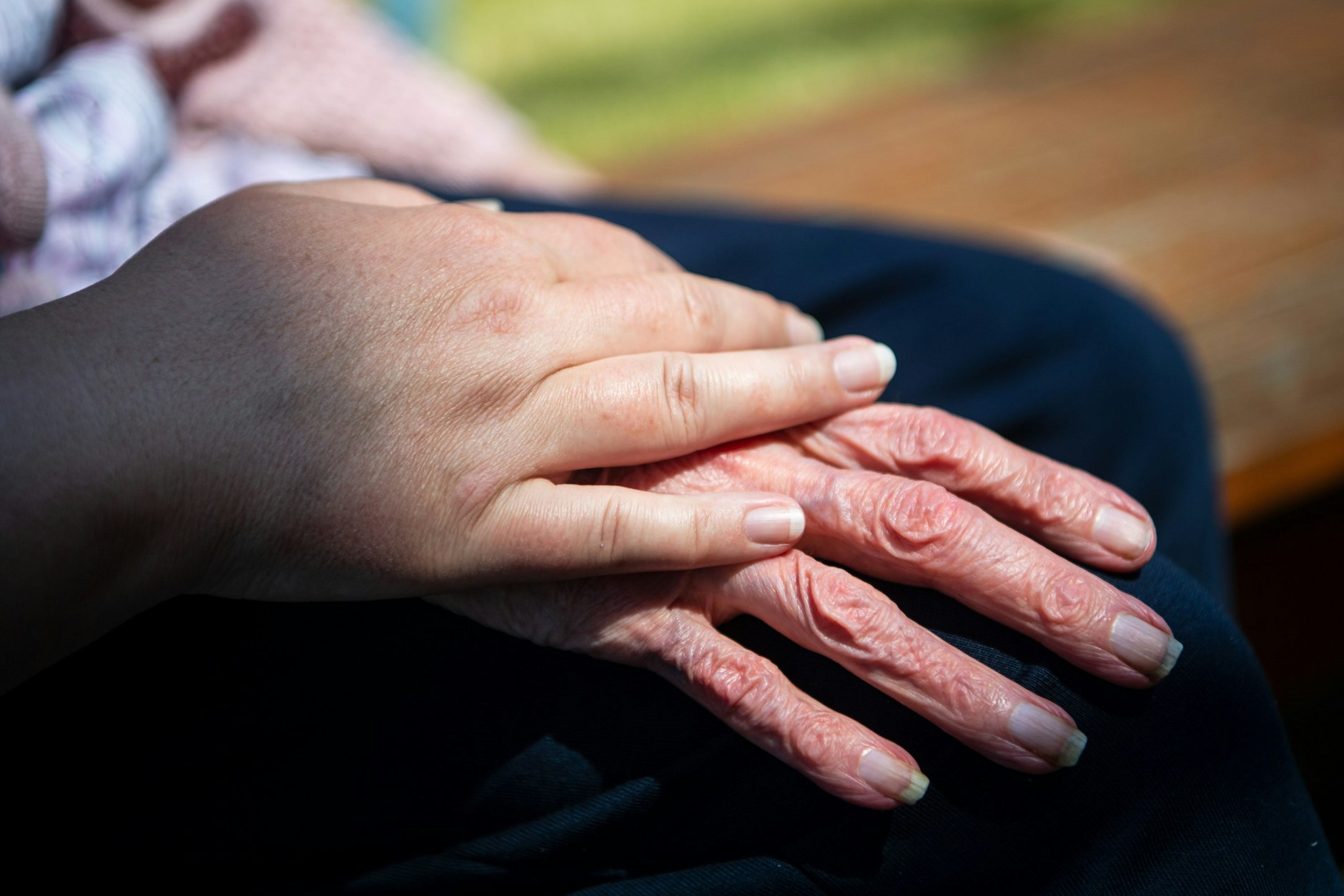 Die Hand einer Pflegefachkraft liegt auf der Hand einer Bewohnerin des Seniorenheims.