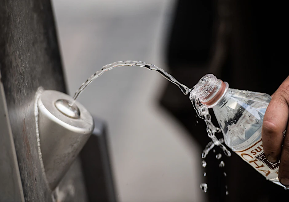 ARCHIV - Ein Mann füllt sich an einem Brunnen kostenlos Trinkwasser in die eigene Flasche.  