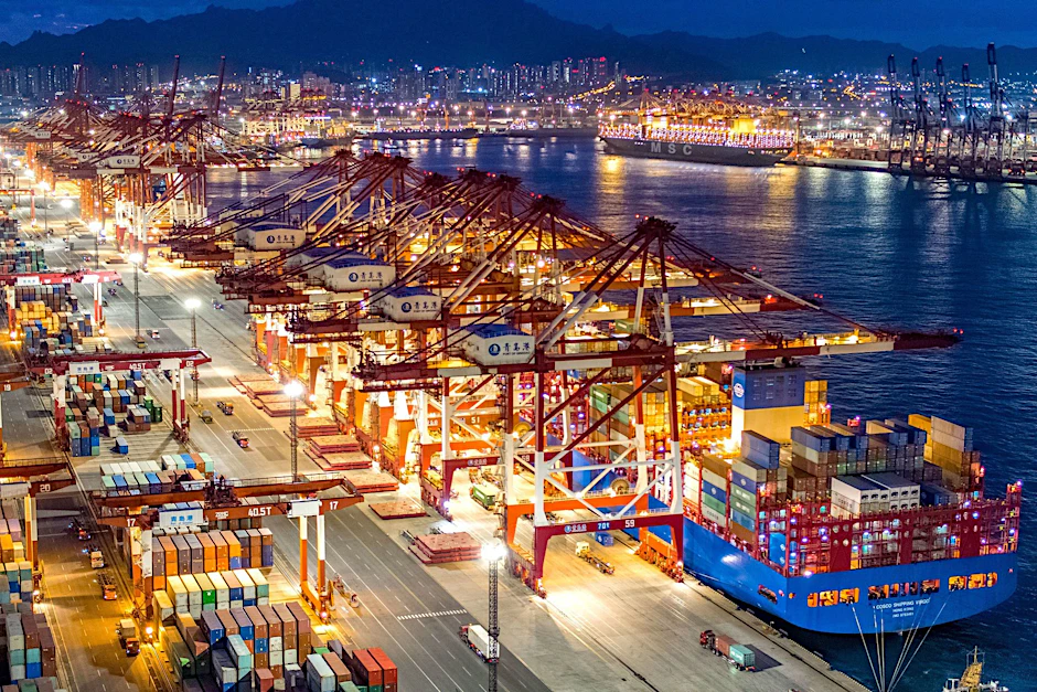 Containerschiffe liegen im nächtlich beleuchteten Containerterminal des Hafens von Qingdao.
