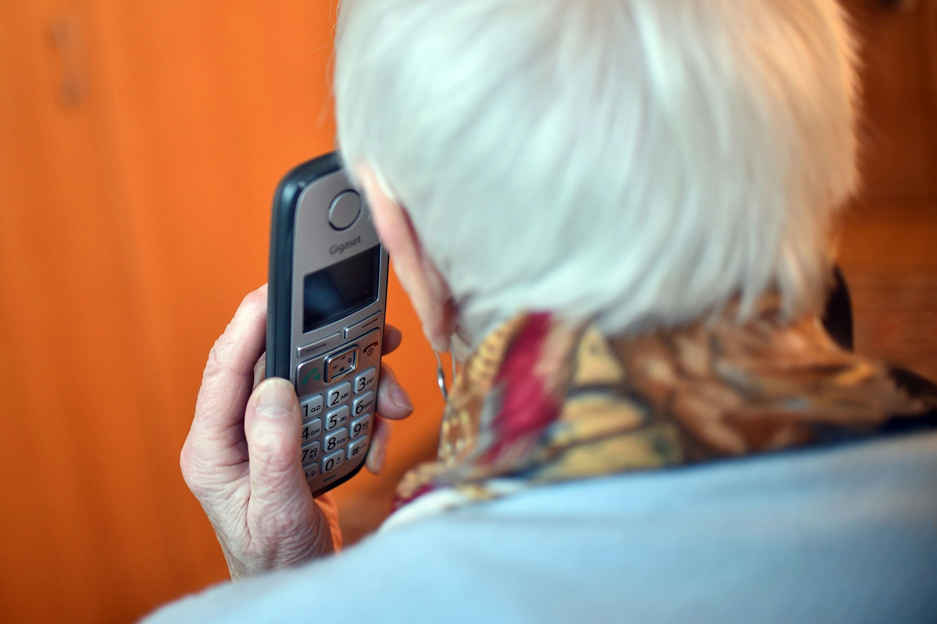 Eine Seniorin hält einen Telefonhörer an ihr Ohr.