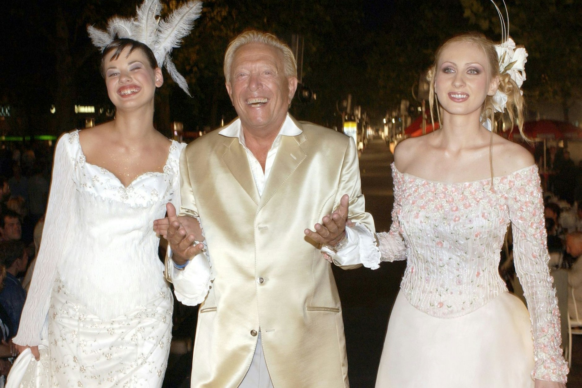 Rolf Eden mit zwei Models auf dem Laufsteg bei der „Coral Fashion Show“ 2002.