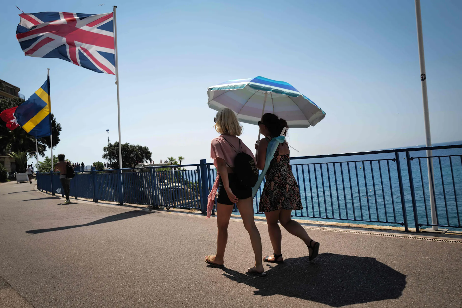 Zwei Frauen gehen mit einem Sonnenschirm auf der „Promenade des Anglais“ in der französischen Riviera-Stadt Nizza, am 17. Juli 2022.