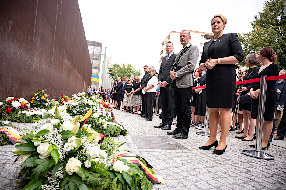 Franziska Giffey (SPD,r), Regierende Bürgermeisterin von Berlin, steht bei der Gedenkveranstaltung für die Opfer von Mauer und Teilung vor den Gedenkkranz vor dem Mahnmal.