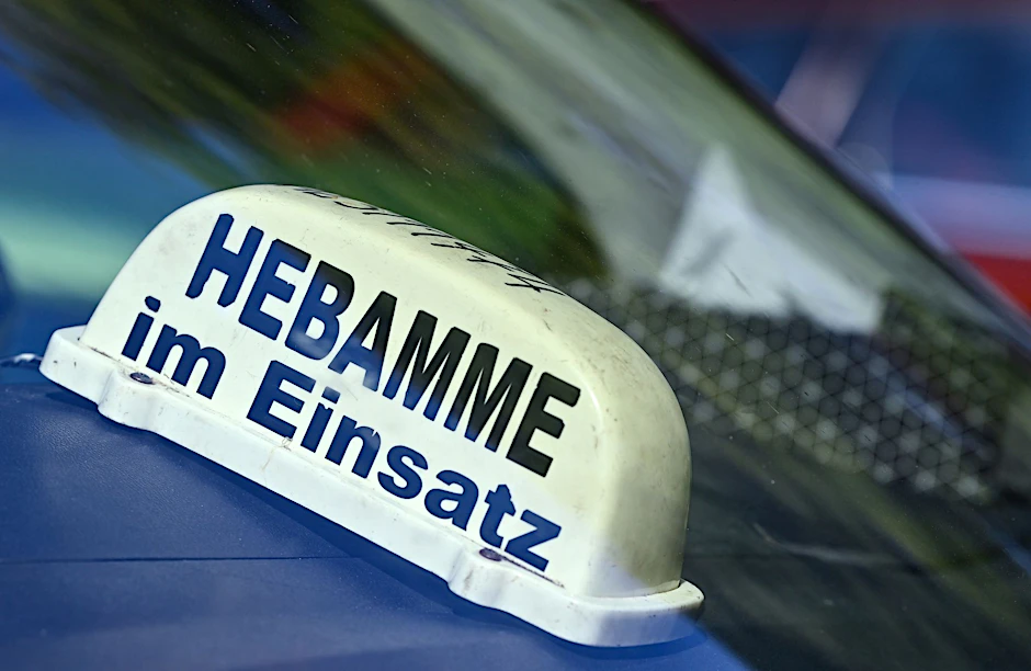 ARCHIV - Ein Schild mit der Aufschrift «Hebamme im Einsatz» liegt in einem Auto.  mbolbild