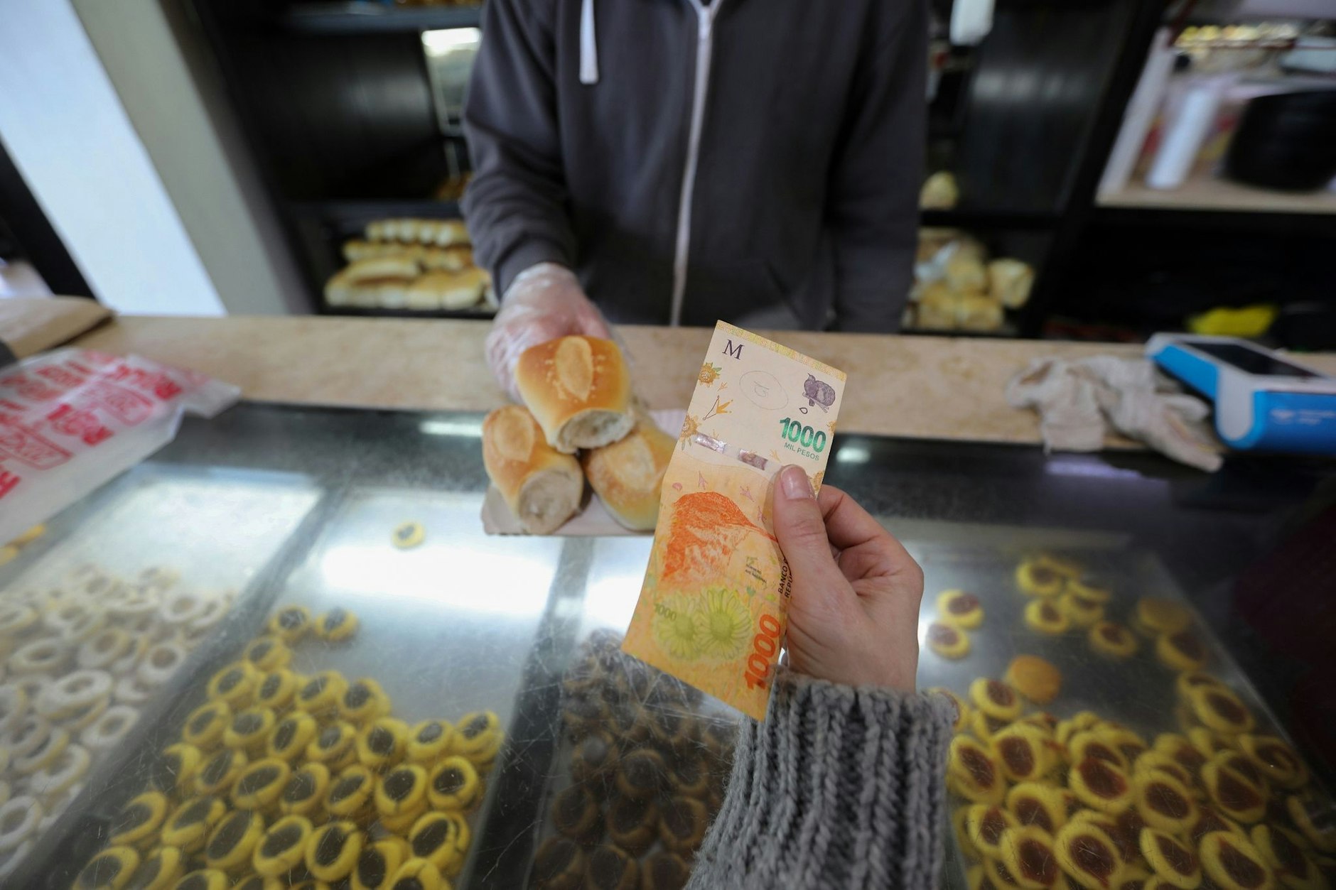 Una mujer paga en una panadería con un billete de 1000 rupias.  