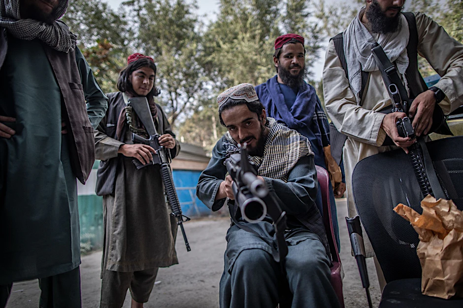 Ein junger Taliban-Kämpfer zielt zum Spaß mit seinem Gewehr in Richtung Fotograf, während er vor einer Polizeistation in Kabul Wache hält.