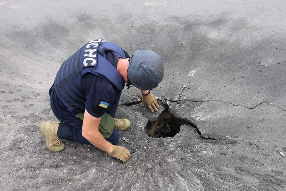 Ein Mitarbeiter des ukrainischen Rettungsdienstes begutachtet einen Krater nach einem Granatenschlag in Charkiw.