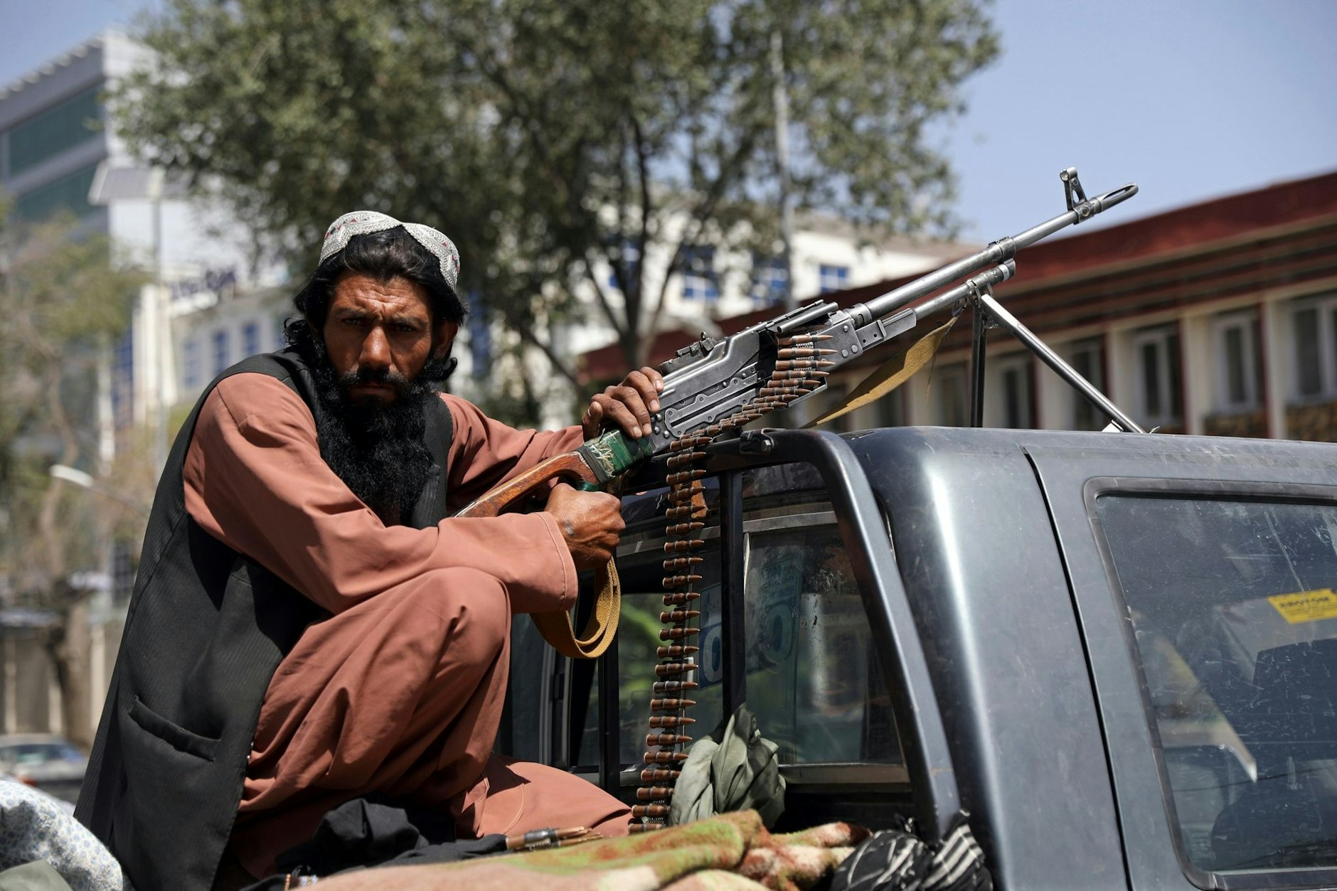 ARCHIV - Ein Taliban-Kämpfer sitzt in Kabul mit einem Maschinengewehr auf der Ladefläche eines Fahrzeugs.  