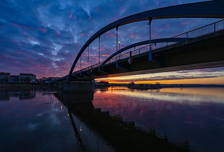 ARCHIV - Die aufgehende Sonne strahlt unter der Stadtbrücke am deutsch-polnischen Grenzfluss Oder.  /Symbolbild