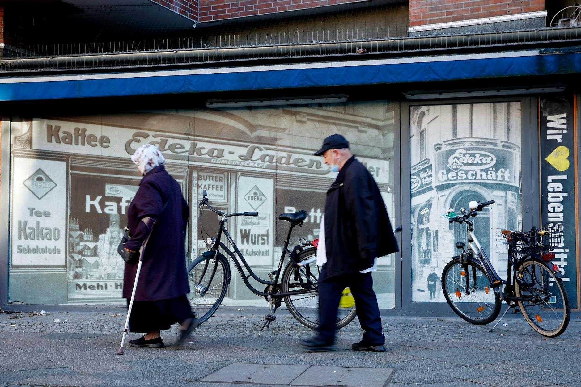 Eine Frau und ein Mann gehen an einem Wandbild im Stadtteil Kreuzberg vorbei.