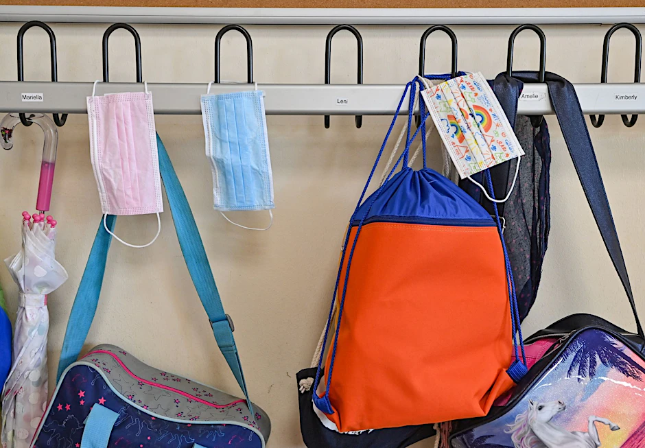 ARCHIV - Medizinische Masken und Schultaschen hängen in einer Schulgarderobe.  /Symbolbild