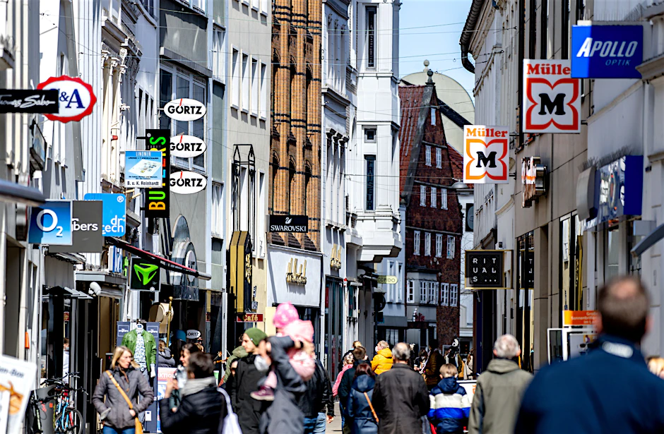 Die Logos zahlreicher Geschäfte hängen an den Fassaden der Häuser in der Innenstadt von Oldenburg. Viele Kommunen suchen nach Wegen, die Stadtzentren attraktiv zu halten und den Leerstand zu vermeiden.