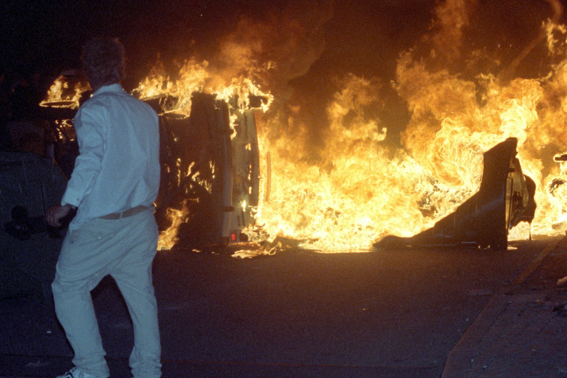 Die Ausschreitungen von 1992: Auf einer Straße am zentralen Asylbewerberheim von Mecklenburg-Vorpommern in Rostock-Lichtenhagen brennt ein Pkw.